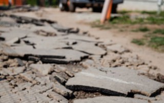 broken pieces of road in need of repair with an orange truck in the background